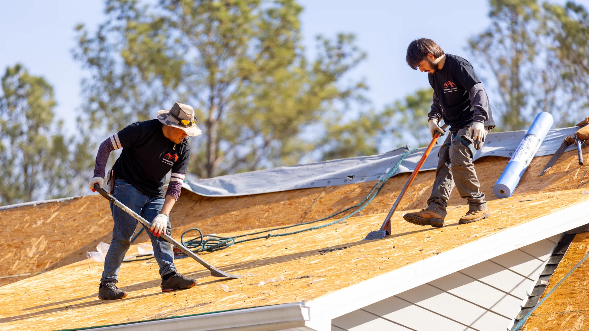 Two McKinley Roofing crew members working on bare roof decking during a roof replacement